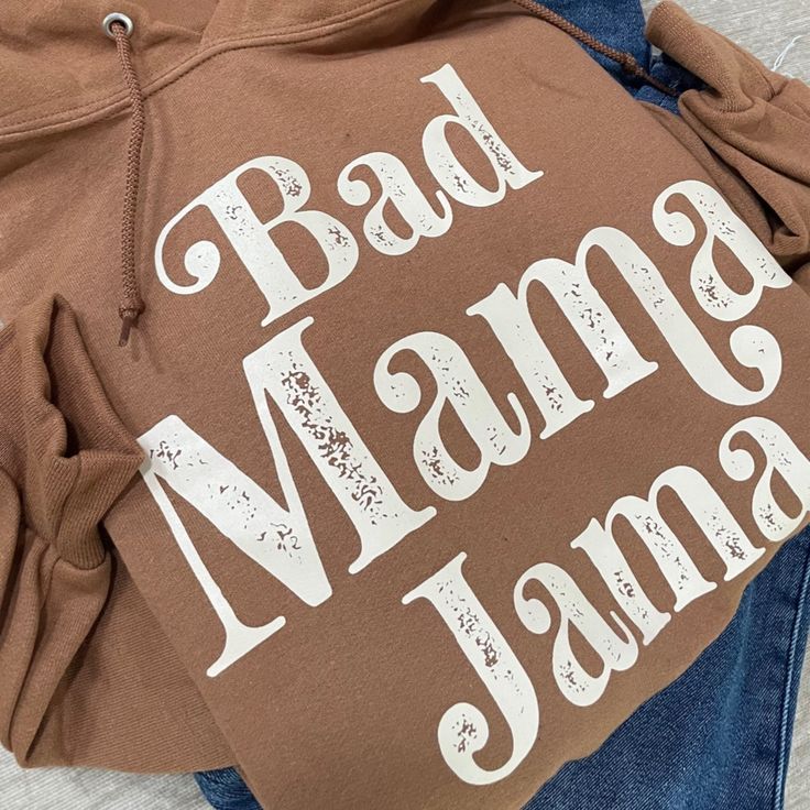 Screen Printed Bad Mama Jama Hoodie made with a cozy 50/50 cotton/polyester blend. Featuring a comfortable hood with a matching drawcord and a convenient pouch pocket, this hoodie is perfect for anyone with its versatile unisex sizing. Choose a range of trendy colors including ocean blue, pecan, coral, heather grey, and classic black, all adorned with a chic cream ink design. Soft and cute to wear oversized must-have hoodie. Size and Fit: Choose normal size for relaxed fit. Soft-washed Cotton Hoodie, Trendy Soft-washed Cotton Hoodie, Soft-washed Cotton Hooded Sweatshirt, Brown Cotton Hoodie With Drawstring, Brown Cotton Hoodie For Loungewear, Brown Cotton Hoodie For Spring, Brown Cotton Hoodie With Kangaroo Pocket, Brown Cotton Hoodie With Adjustable Hood, Brown Cotton Sweatshirt With Adjustable Hood