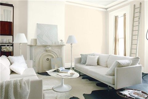 a living room filled with white furniture next to a fire place in a fireplace mantel