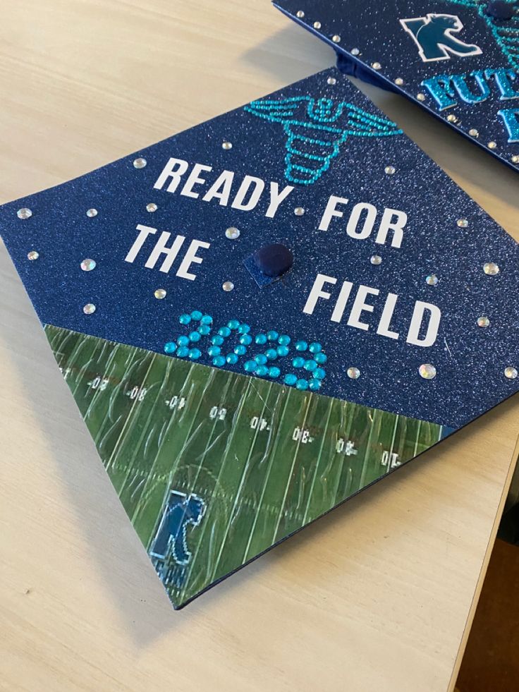 two blue graduation caps with the words ready for the field on them sitting on a table