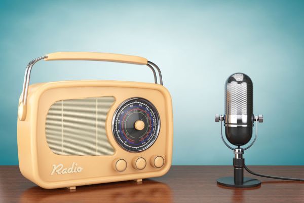 an old radio next to a microphone on a wooden table in front of a blue wall