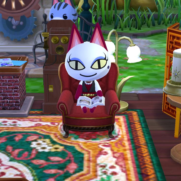 a cat sitting in a chair reading a book on top of a rug next to a fireplace