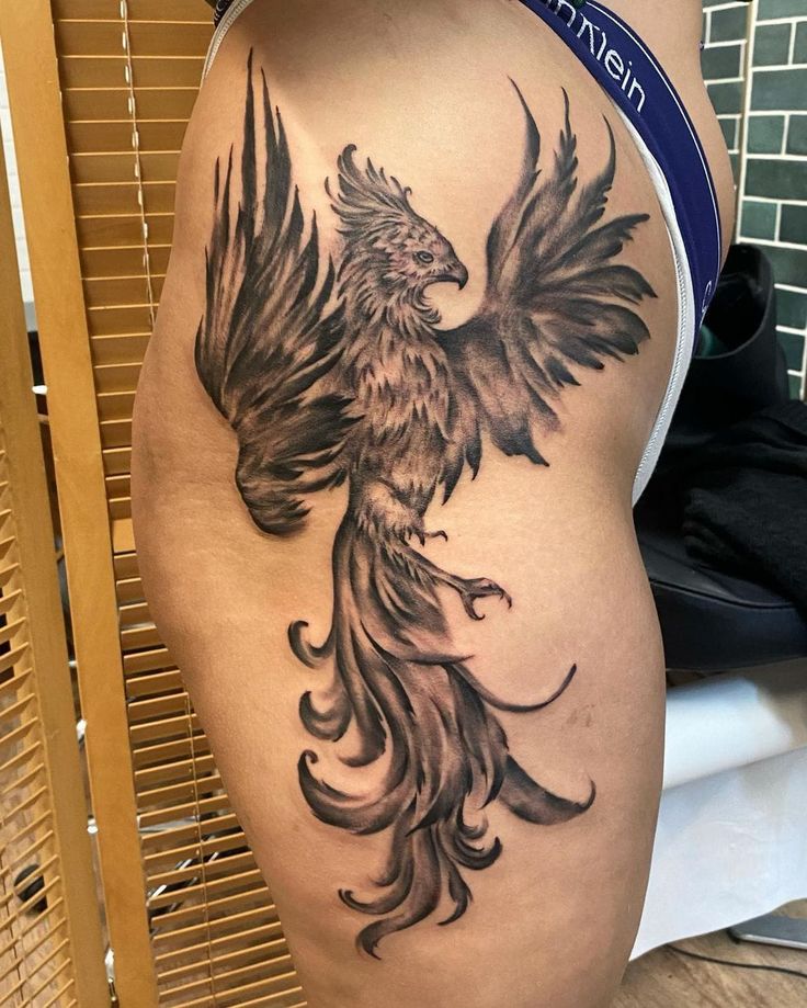 a woman's thigh with a tattoo of a bird on the side and wings