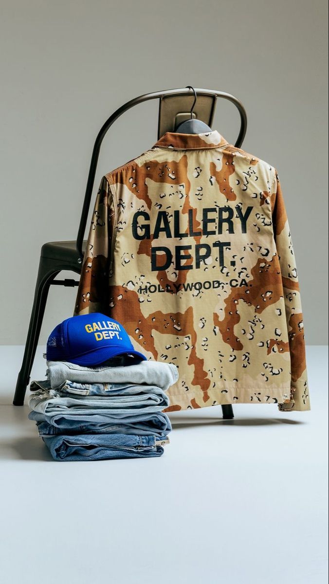 a shirt that is sitting on a chair next to some folded jeans and a hat