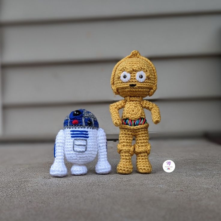 two crocheted toys are standing next to each other in front of a house