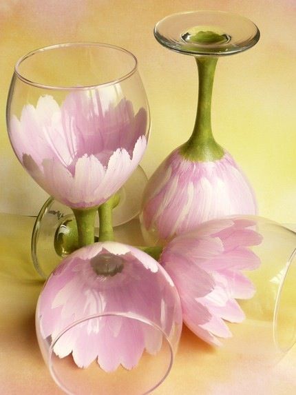 three wine glasses with pink flowers in them on a yellow and pink background, one is filled with water