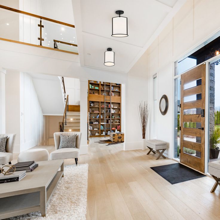 a living room with wooden floors and white furniture in front of a large open door