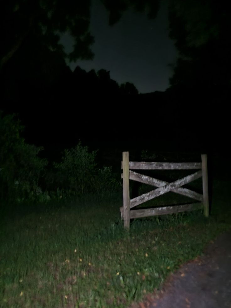 a wooden fence sitting in the grass at night