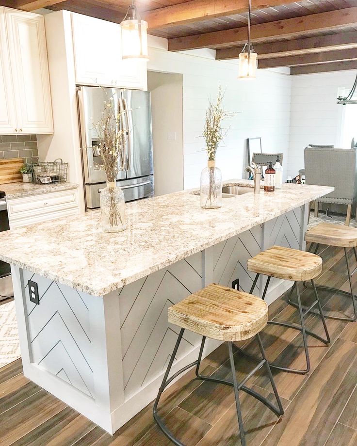 a kitchen island with three stools in the middle and an open floor plan behind it