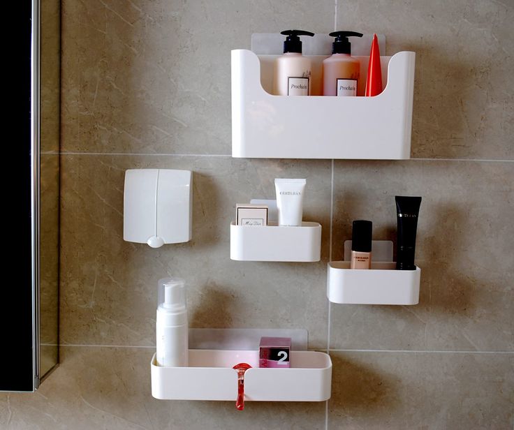 two white shelves with soap, lotion and other items on them in a bathroom