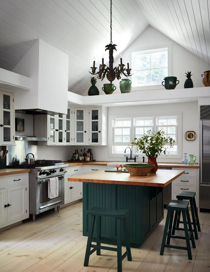 a kitchen with white cabinets and green island