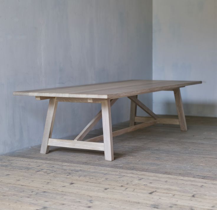 a wooden table sitting on top of a hard wood floor next to a gray wall