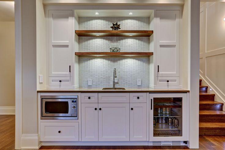 an open kitchen with white cabinets and wood flooring in the center is lit by recessed lighting