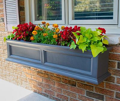 a window box filled with colorful flowers next to a brick building