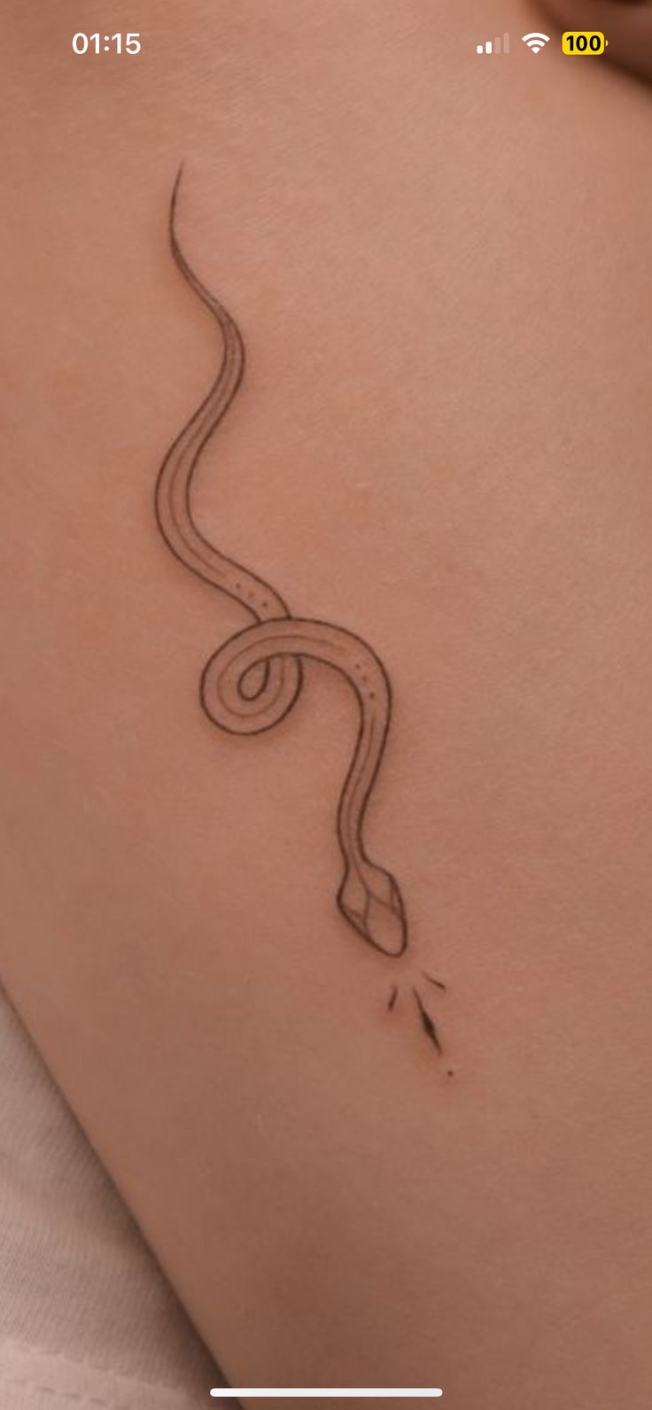 a woman's thigh with a snake tattoo on the side and an arrow in the middle