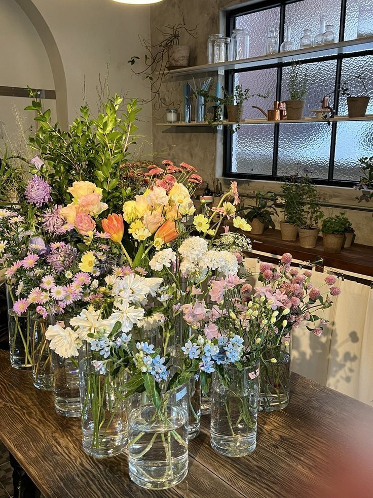 several vases filled with flowers on top of a wooden table