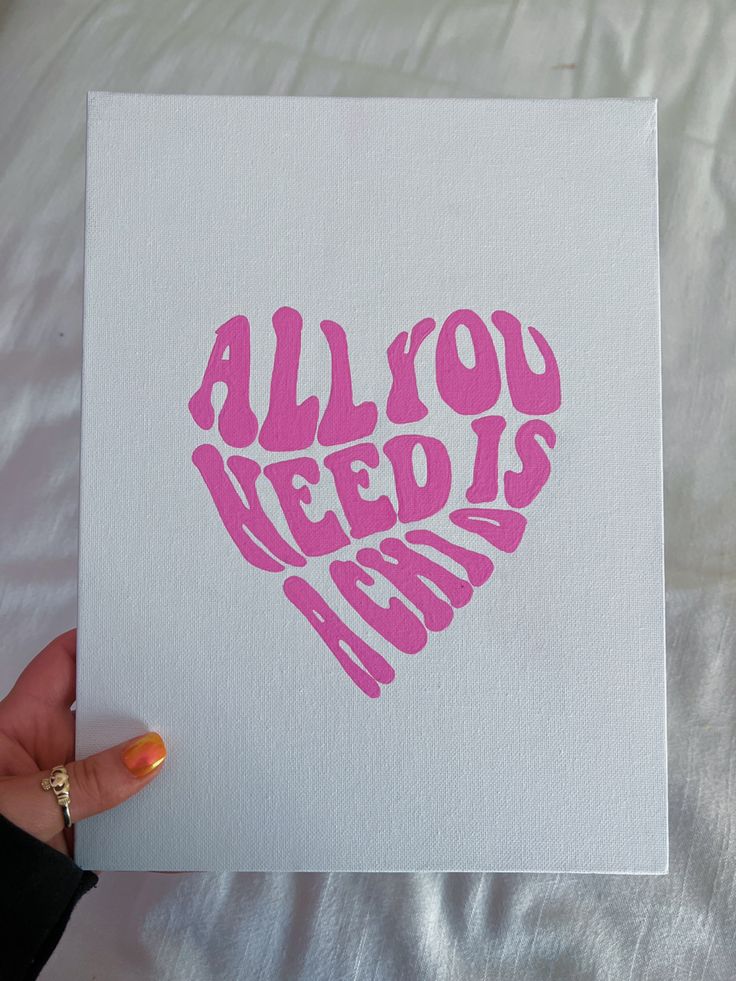 a hand holding up a pink heart shaped card with the words all you need is love