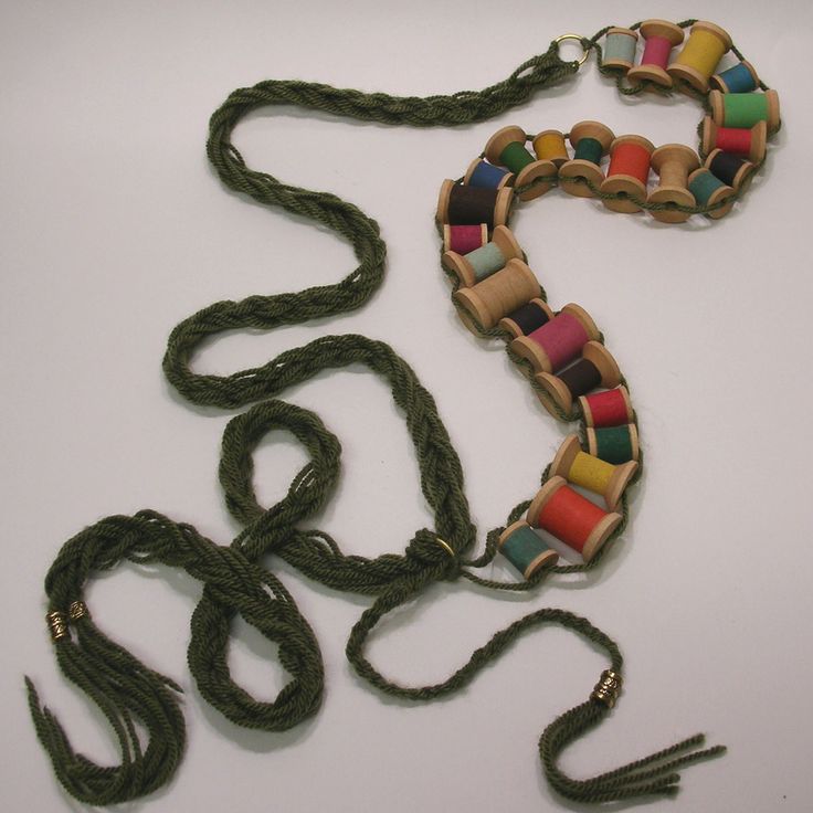 a multicolored beaded necklace on a white table with other beads and cords