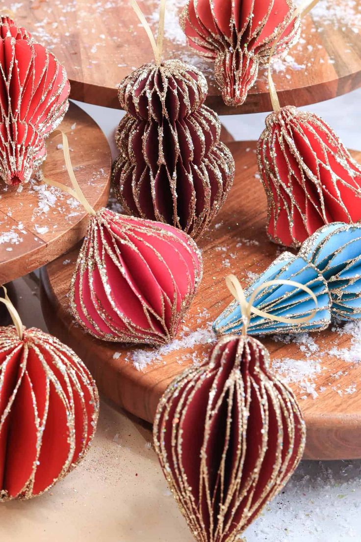 some red and blue ornaments are sitting on a wooden board with snow around them in the background