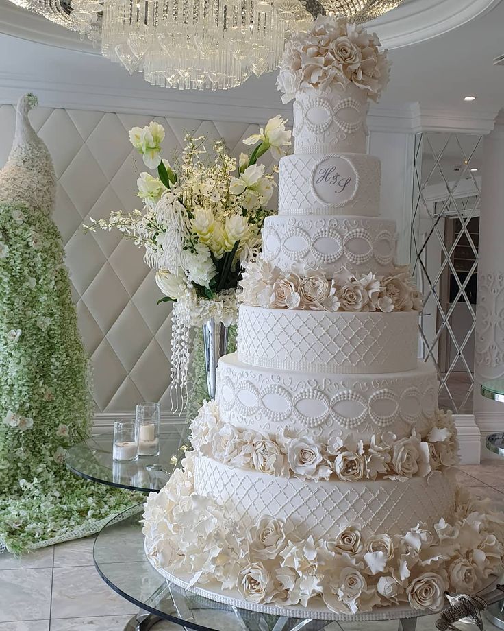 a large white wedding cake sitting on top of a table next to a vase filled with flowers