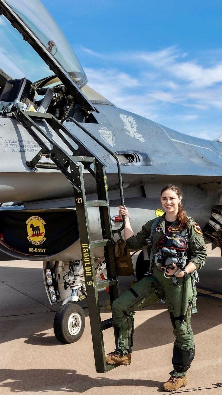 a woman is standing next to a fighter jet