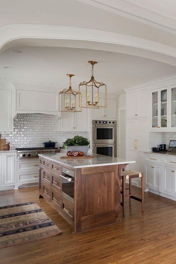 a large kitchen with white cabinets and wood flooring, an island in the middle