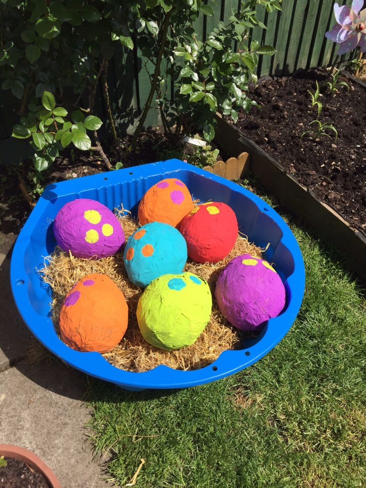 a blue bowl filled with colorful balls on top of grass