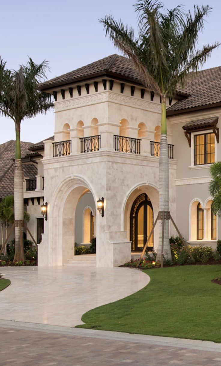 a large white house with palm trees in the front yard and walkway leading to it