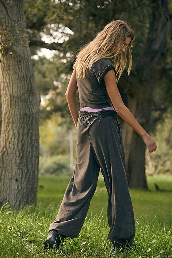 a woman standing in the grass with a frisbee behind her back to the camera