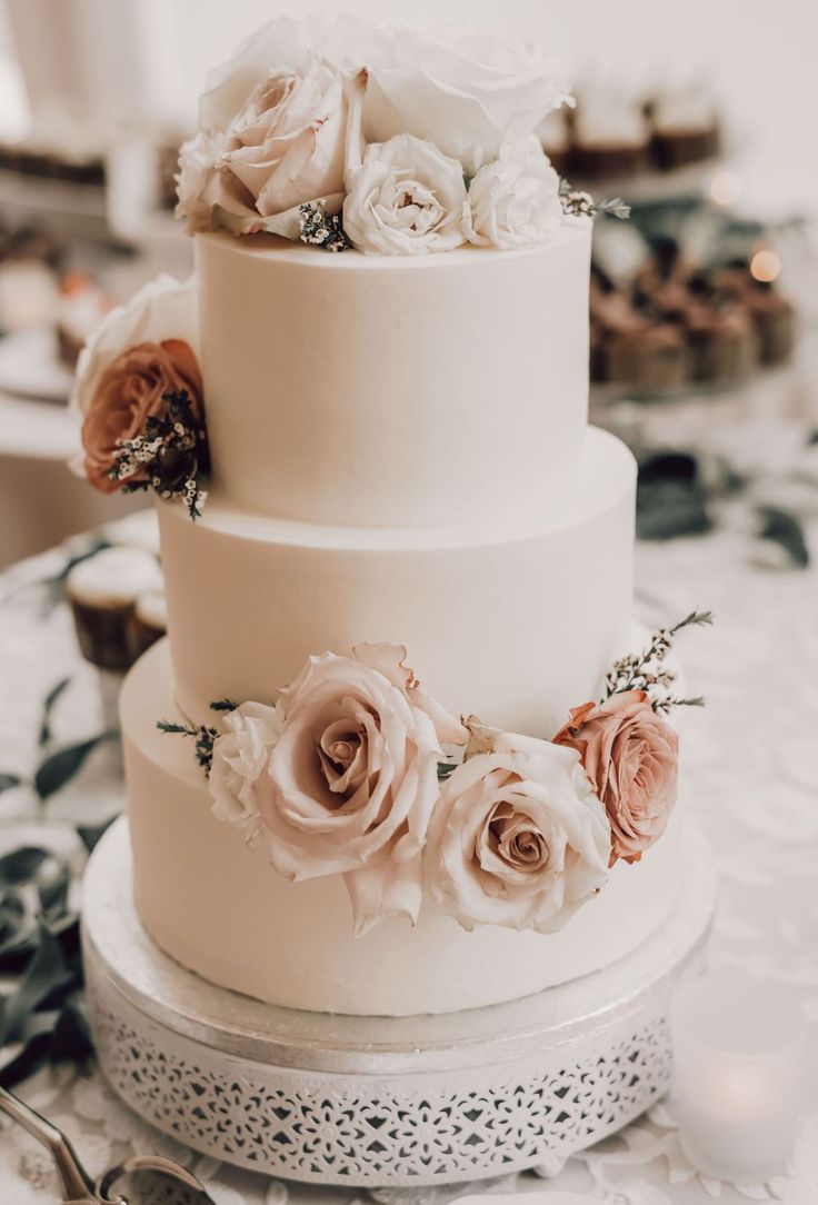 a three tiered wedding cake with white and pink flowers