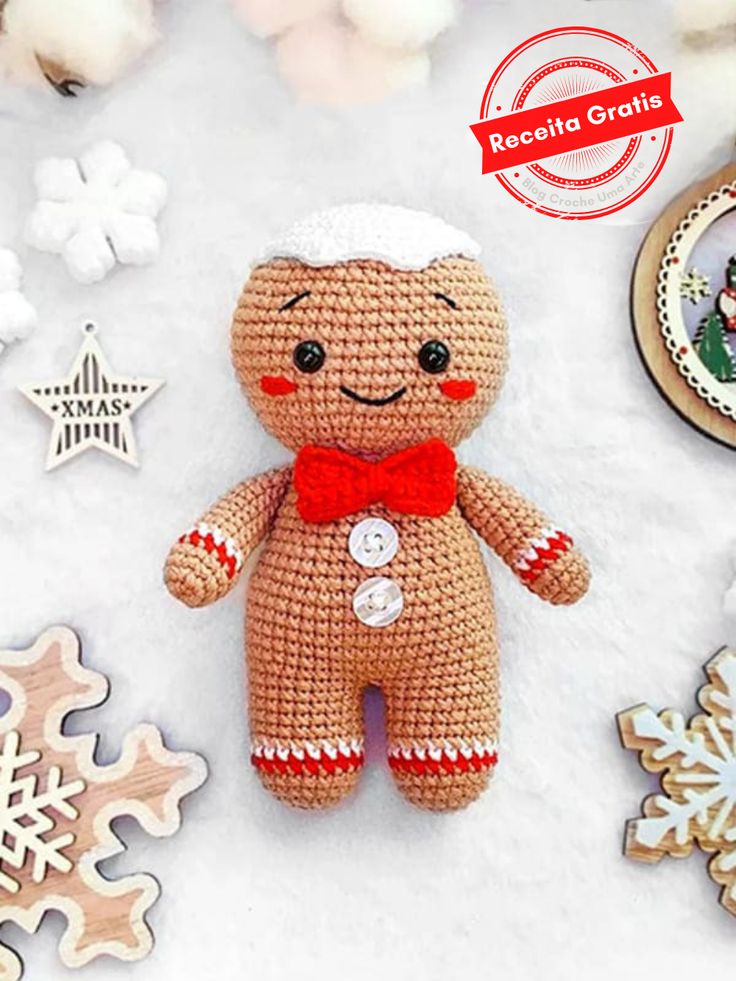 a crocheted teddy bear with a red bow tie and snowflakes around it