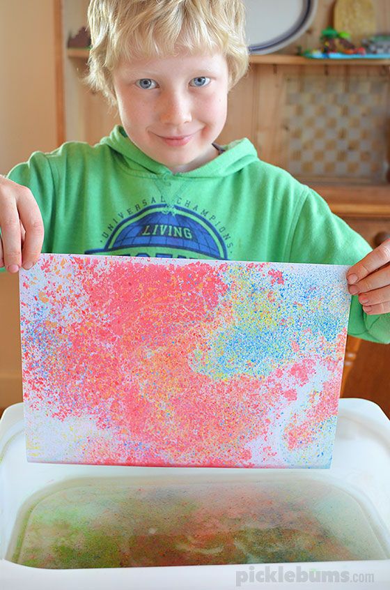 a young boy holding up a painting in front of him