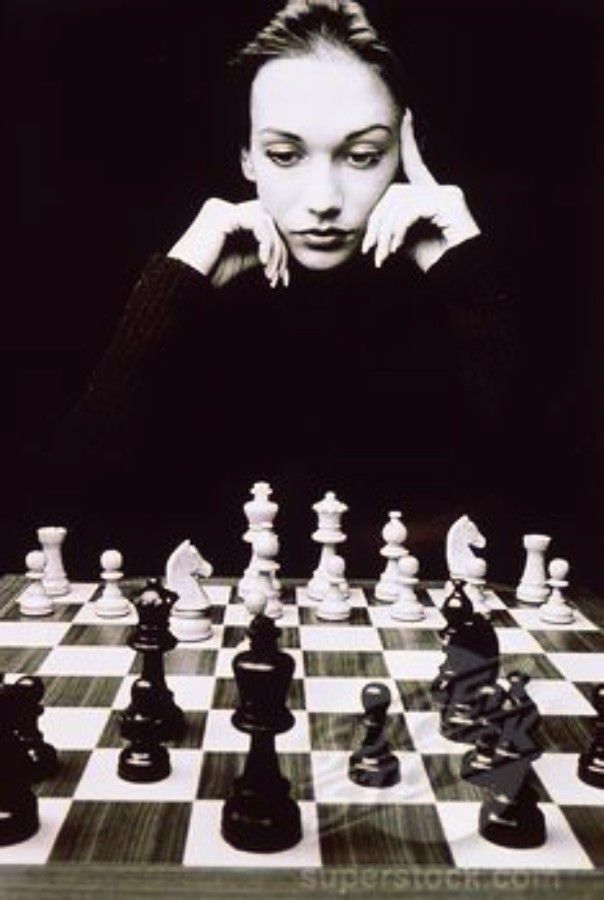 a black and white photo of a woman playing chess