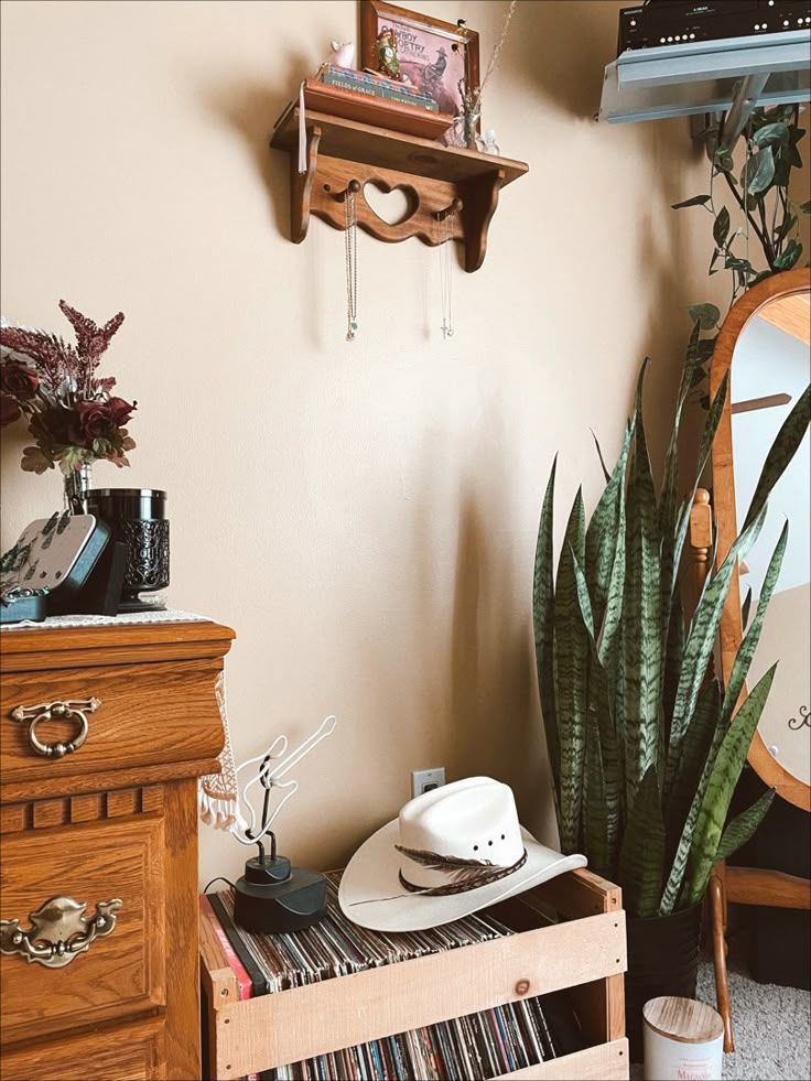 there is a hat on top of a record player in the corner next to a potted plant