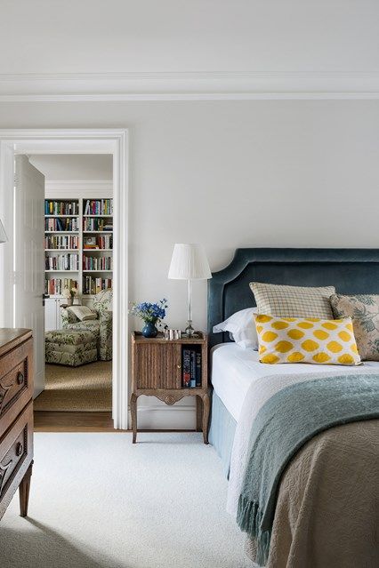 a bedroom with a bed, dresser and bookshelf in the corner is shown