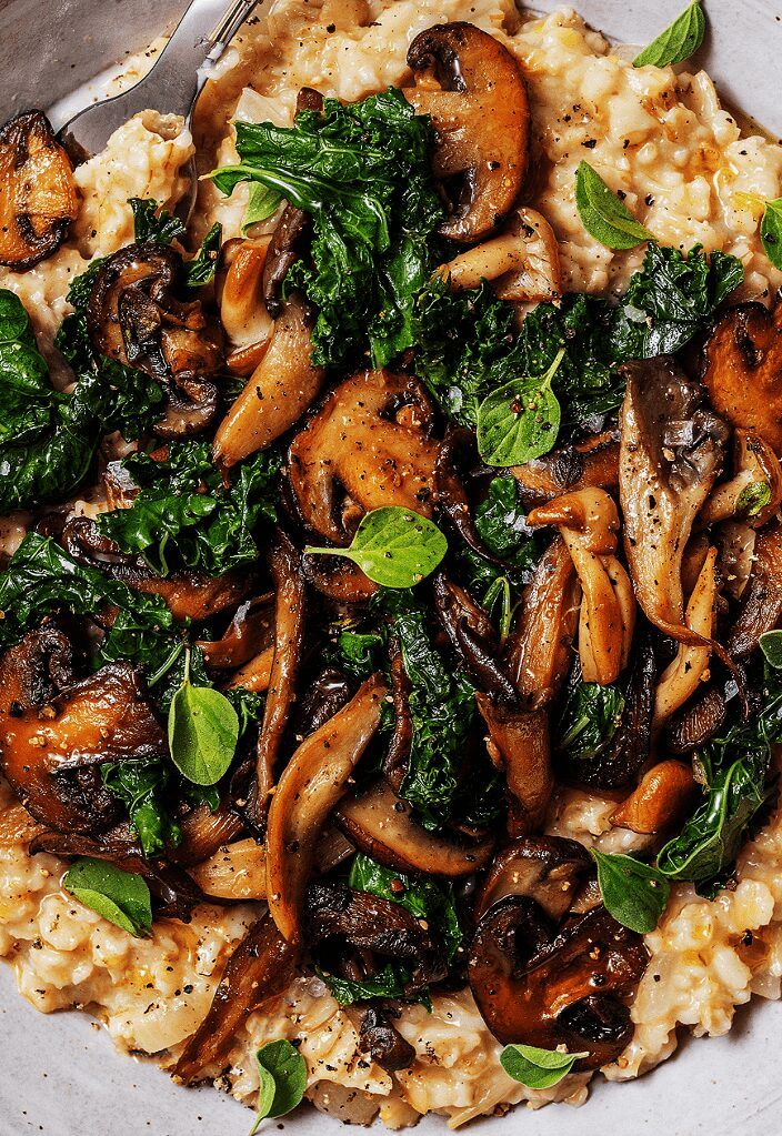 a white plate topped with rice covered in mushrooms and spinach next to a fork