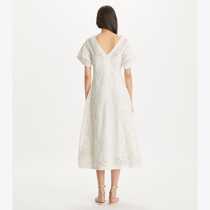 The v-neck dress has a vintage-inspired silhouette, expertly constructed in embroidered linen and cotton. Flattering and versatile, with a nipped-in waist, flutter sleaves and a tea-length skirt. Elegant Spring Embroidered Linen Dress, Embroidered V-neck Midi Dress For Garden Party, Elegant Embroidered Linen Dress For Spring, Elegant Linen Embroidered Dress For Spring, Elegant V-neck Dress With Chikankari Embroidery, Elegant Linen Dresses With Broderie Anglaise, Elegant V-neck Chikankari Embroidered Dress, Summer Linen Dress With Broderie Anglaise, Linen V-neck Dress With Floral Embroidery