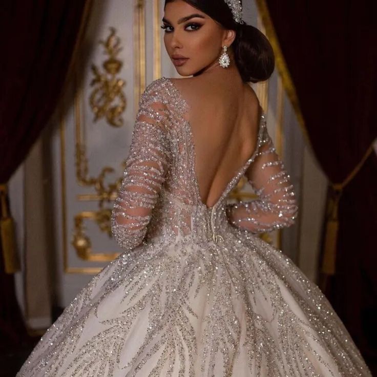 a woman in a wedding dress standing next to a wall with gold and white decorations