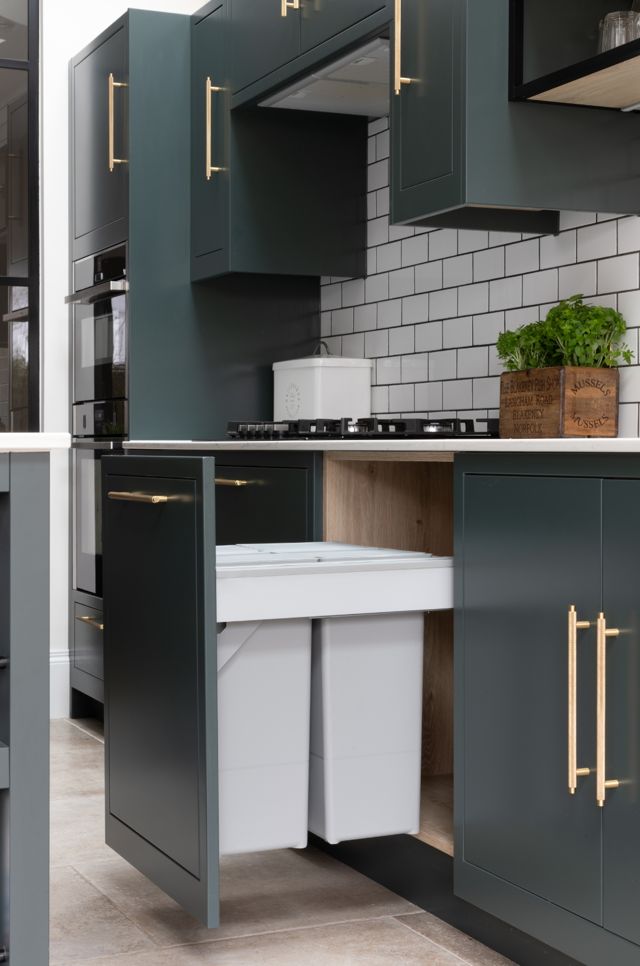 a kitchen with grey cabinets and white counter tops, gold handles on the doors is shown