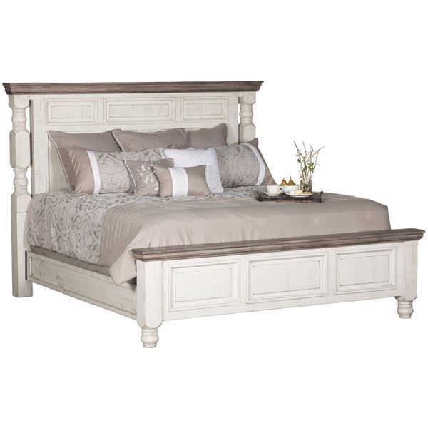 a large white bed sitting next to a night stand with pillows on top of it