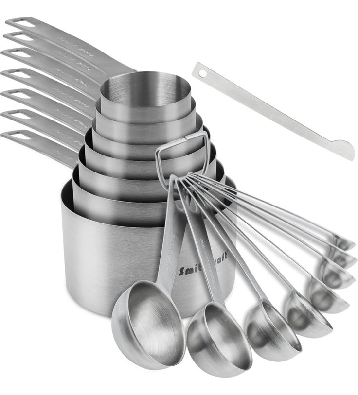 stainless steel utensils and measuring spoons are arranged in a pyramid on a white background