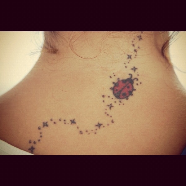 a ladybug tattoo on the back of a woman's neck