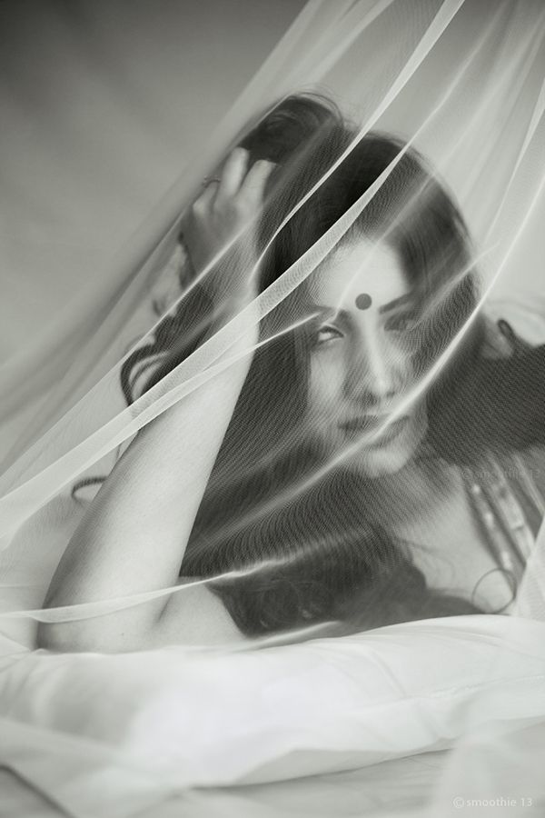 a woman with her hands on her head and veil over her face, in black and white