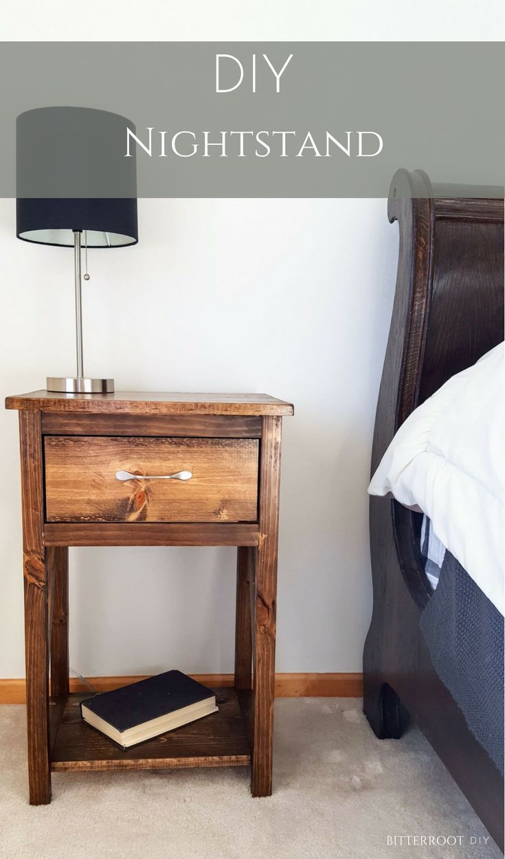 a wooden night stand with a book on it next to a lamp and a bed