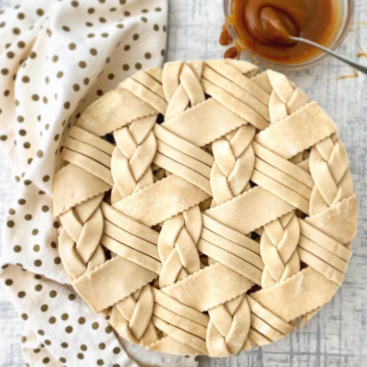 an uncooked pie sitting on top of a table next to a cup of peanut butter