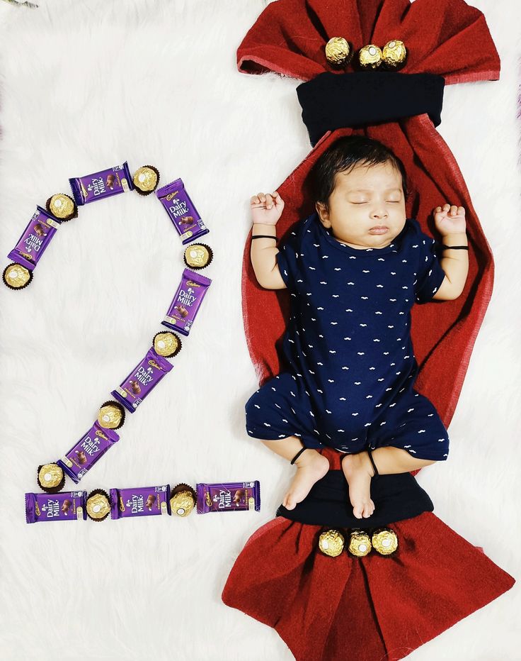 a baby is laying on its back next to some chocolates and a red blanket