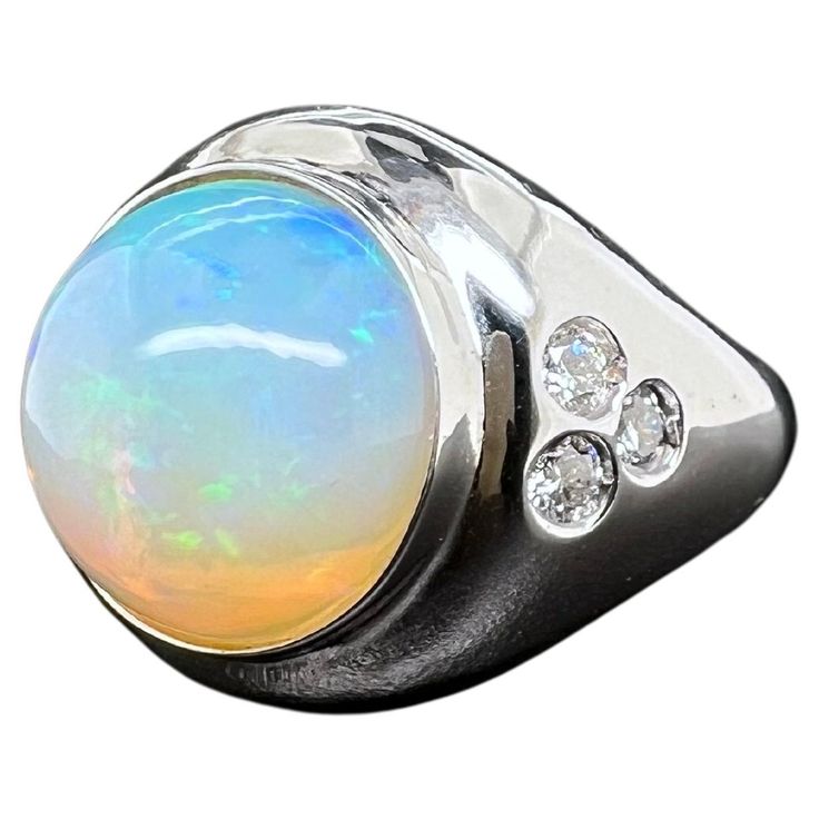 This stunning Ethiopian opal men's ring is a must have for any collection. The round opal glows with green, blue and yellow hues. The diamonds are inlayed on the sides to give a nice accent to the sleek ring. The overall design of the ring is made to be worn comfortably and will not catch on apparel. Ring Size: 12.75 (can be sized) Diamonds 0.58 ct. Round Brilliant Ethiopian Opal: 11.20 cts, Round Cabochon Metal: 14k White Gold Ethiopian Men, Opal White, Men Ring, Domed Ring, Men's Ring, Blue And Yellow, Ethiopian Opal, Round Brilliant, Diamond Rings