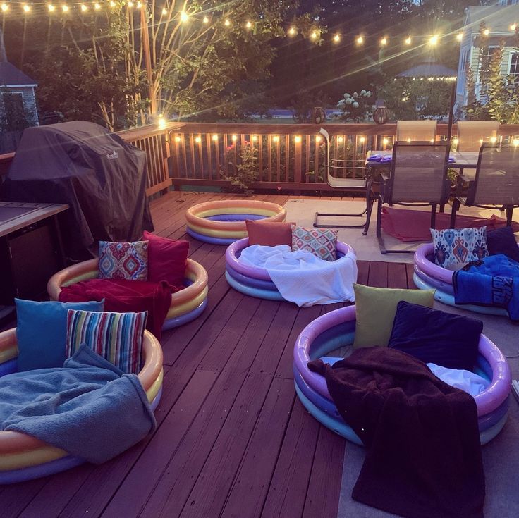 an inflatable pool on a deck with lights strung over the back yard and patio furniture