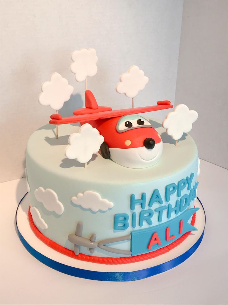 a birthday cake decorated with an airplane and clouds