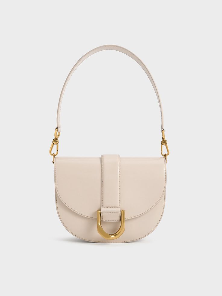 Update your Gabine collection with this oat-white leather version, exuding understated elegance and timeless luxury. Designed for the modern woman, the Gabine bag is perfect for both daytime outings and after-dark events. Its iconic design remains unchanged, from the U-shaped buckle to the classic saddle silhouette, along with the single handle, which can be swapped for a longer shoulder strap for hands-free convenience and versatile styling options. Timeless Luxury, Leather Saddle Bags, Charles Keith, Iconic Design, Understated Elegance, Saddle Bag, After Dark, Hands Free, Saddle Bags