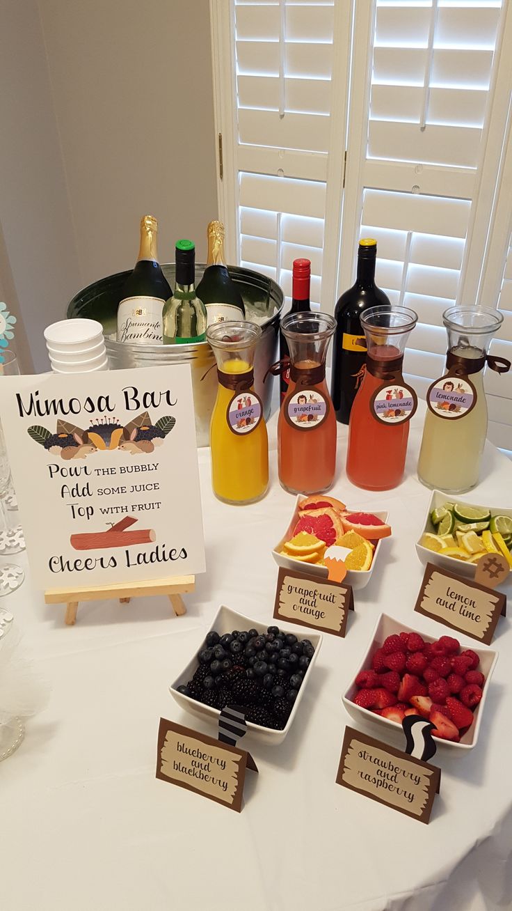 a table topped with lots of different types of fruit and drinks next to a sign